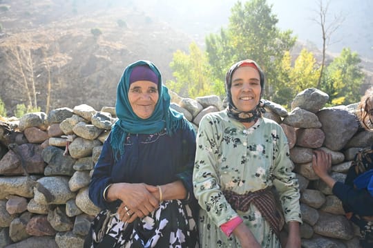 two women sitting on a rock wall